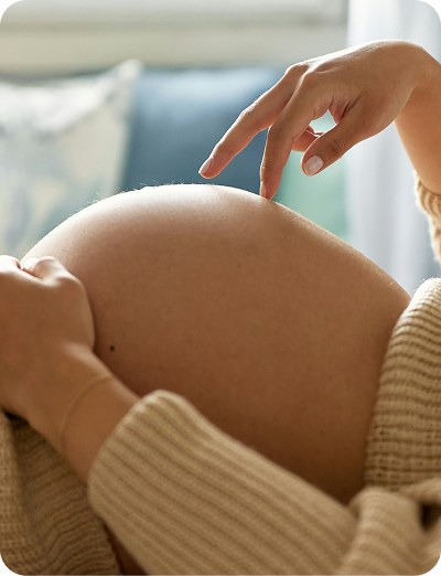 woman touching her pregnant belly with a hand in a blurred indoor setting